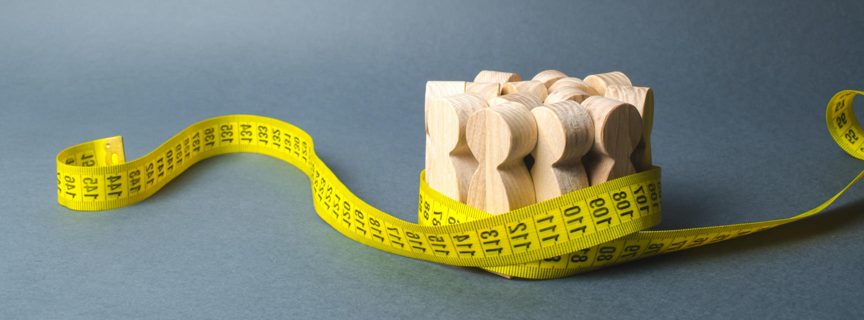 Group of wooden figures gripped by measuring tape