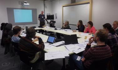 Group of ESRC teachers' workshop participants sitting in small classroom 
