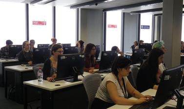 View from the front left of students of Summer Institute sitting behind desktop computers looking to the front