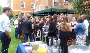 Summer Institute participants and lecturer at welcome reception in garden outside red building 
