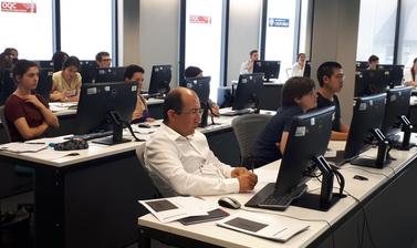 Side view of students of Summer Institute sitting in computer lab room listening to lecturer