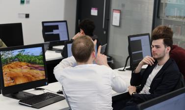 Q-Step instructor sitting next to male student and helping him with practical data analysis task