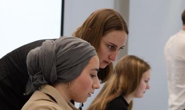 Q-Step instructor helping female student with coding task on computer