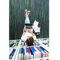 Student sitting on the floor in a library, doing research on laptop